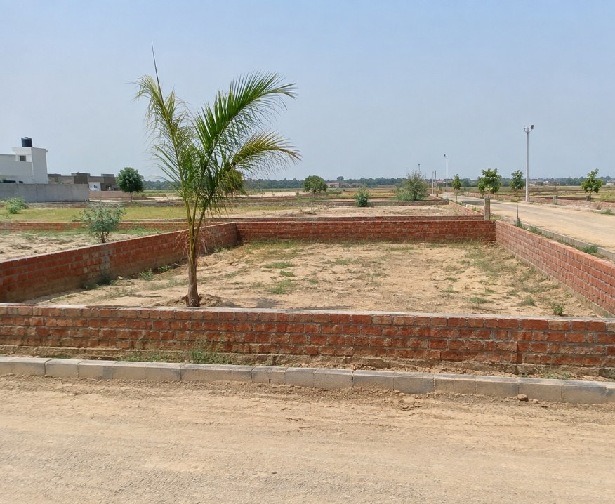 Raw open plot with a low brick boundary, typical of corridor listings